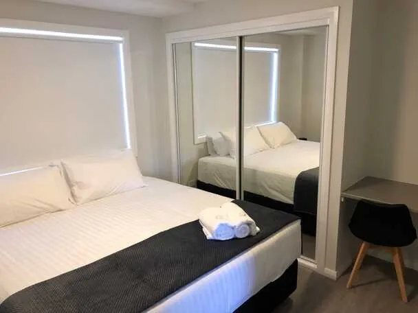 Apartment bedroom with mirrored wardrobe and modern chair