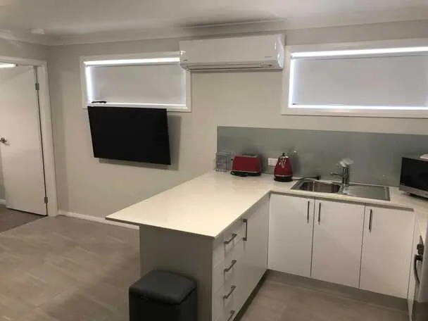 Compact kitchenette with wall-mounted television and split-system air conditioning