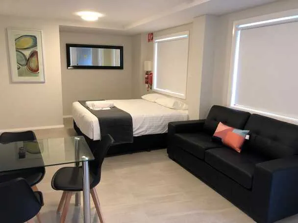 Wide view of a William Lodge studio apartment showing the bed, sofa and dining area together